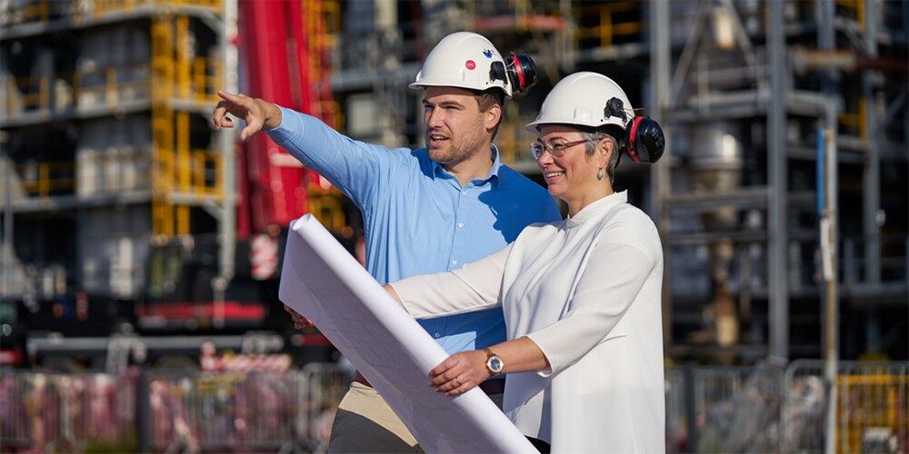 Two colleagues in a plant look at blueprints